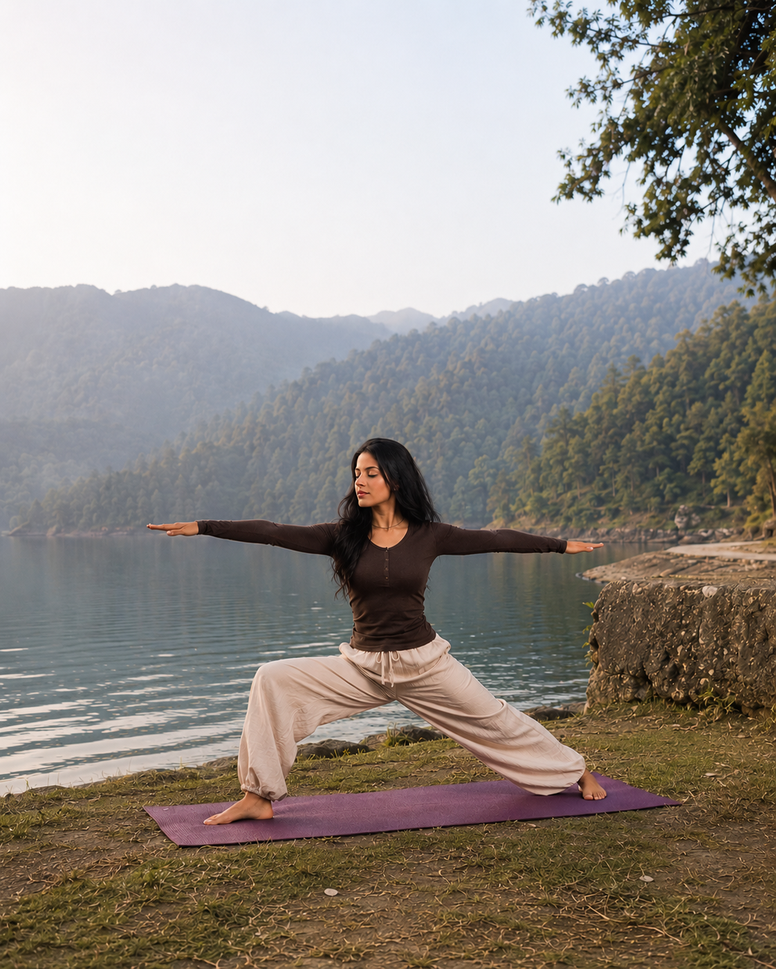 Shuchita practicing a grounding standing pose by a still mountain lake at sunrise, arms extended in calm, grounded alignment.